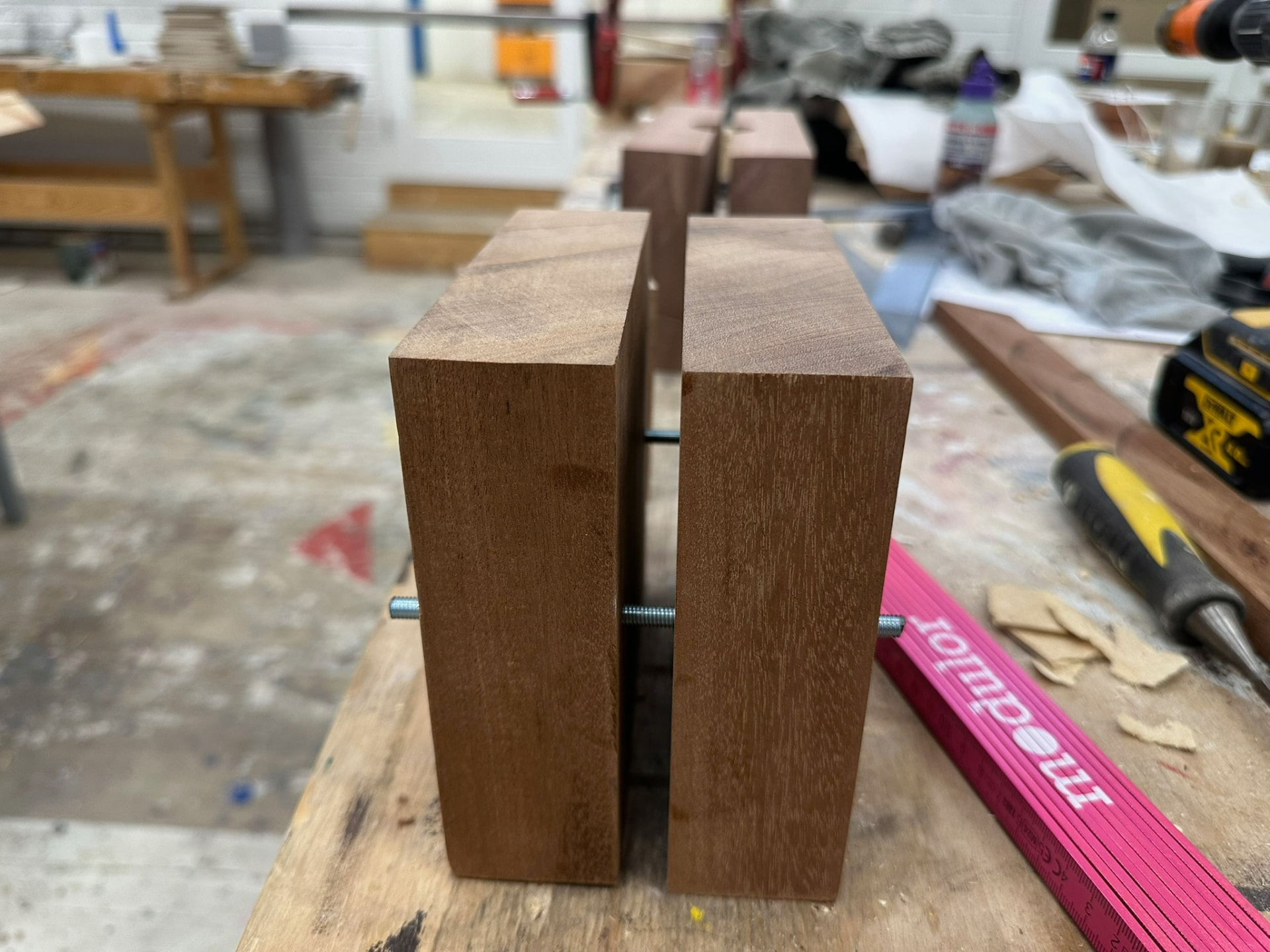 Two walnut blocks clamped together with threaded rod on a workbench.