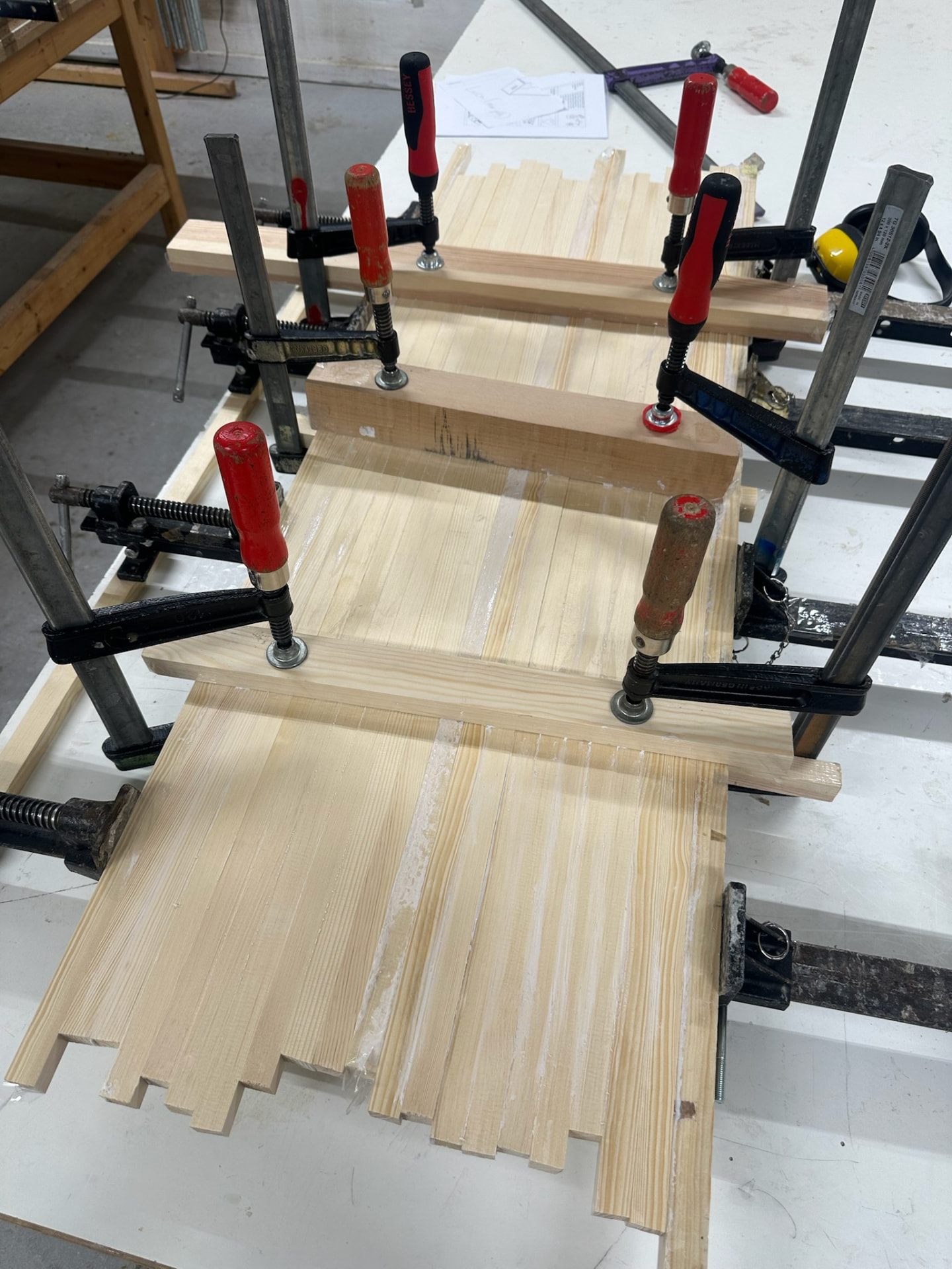 Pine panels glued and held in clamps on a bench.