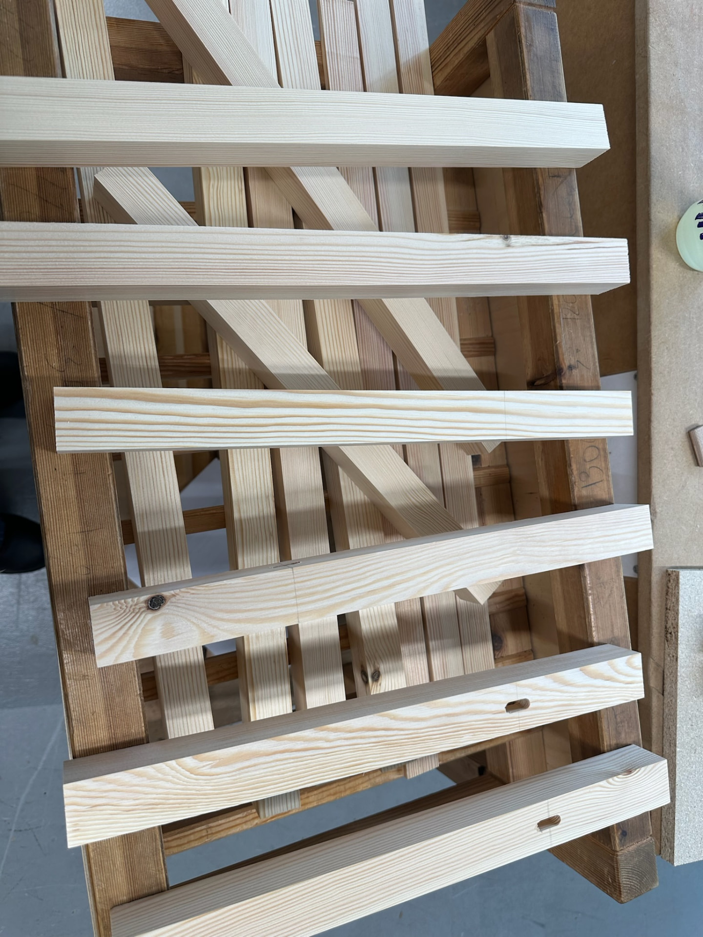 Planed pine bench frame parts laid out on a rack in the workshop.