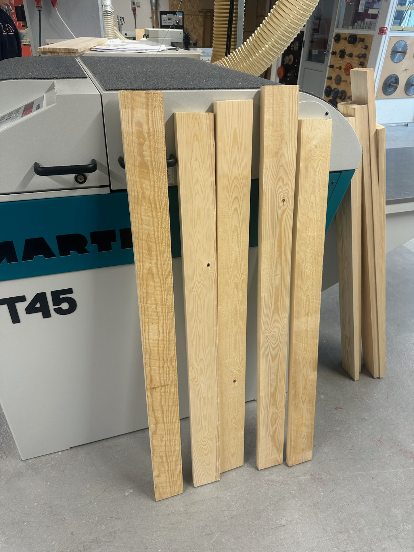 Planed pine components leaning against a Martin T45 machine in the workshop.