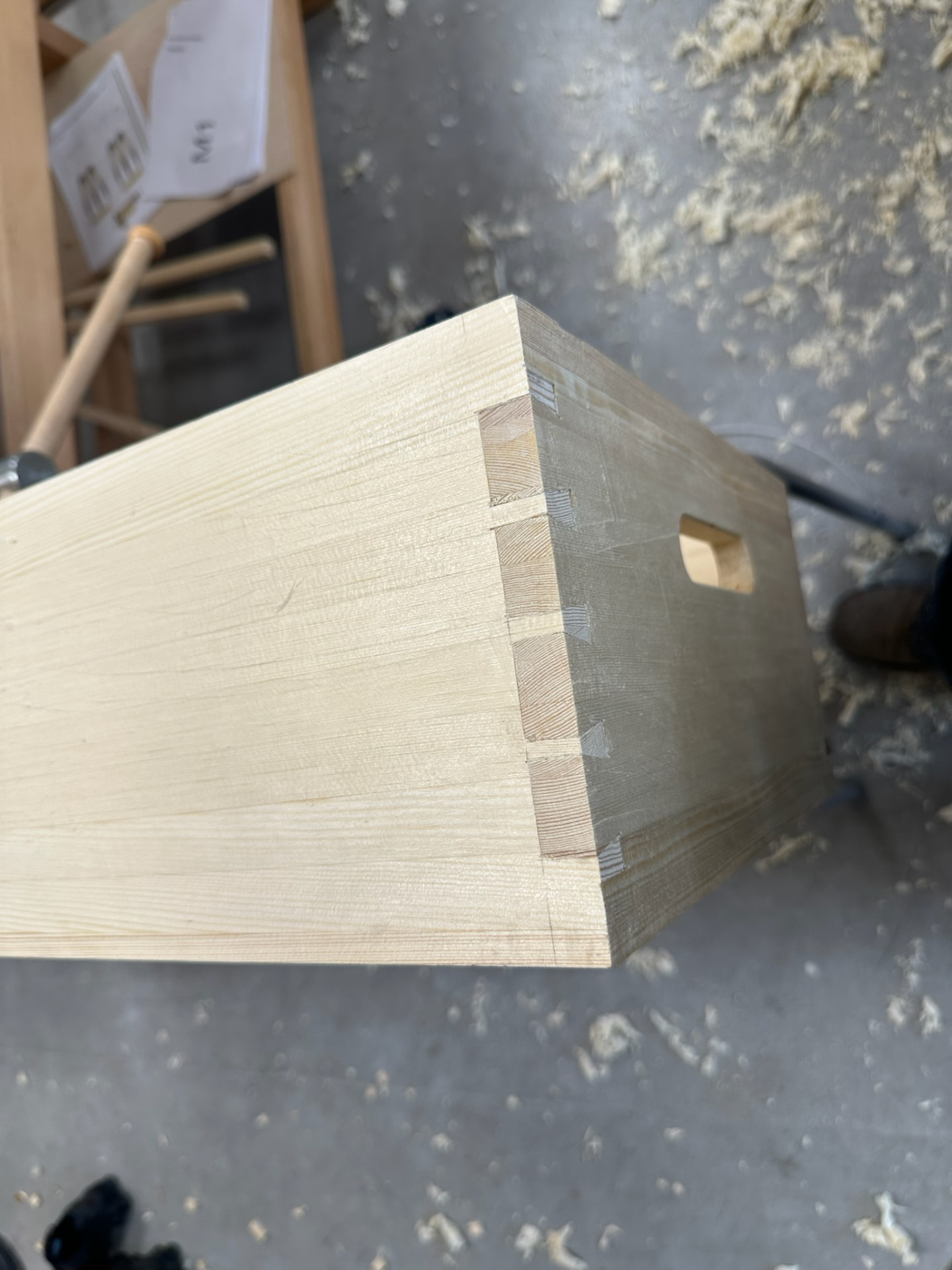 Close-up of a hand-cut dovetailed corner on a pine box with a routed handle.