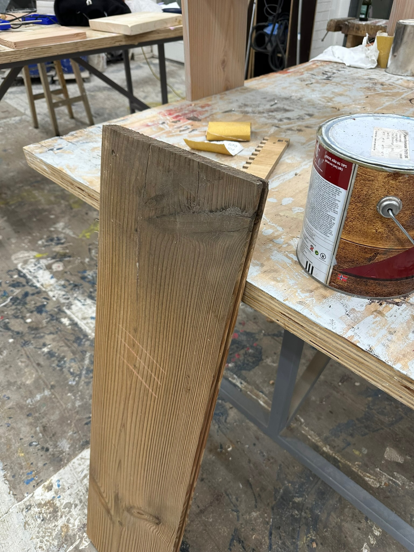 Bench leg with finishing oil and sandpaper on the workbench.