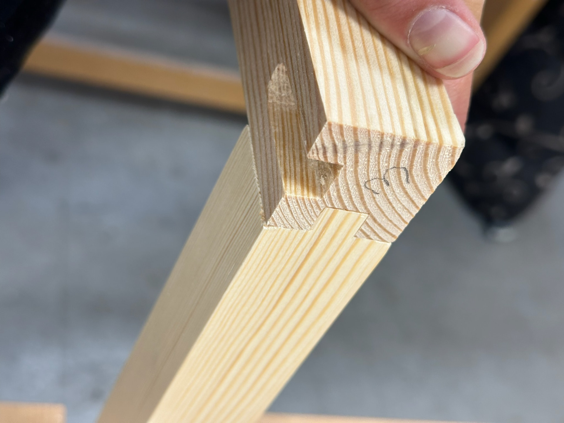 Close-up of a hand-cut joint in pine, held up to the light.