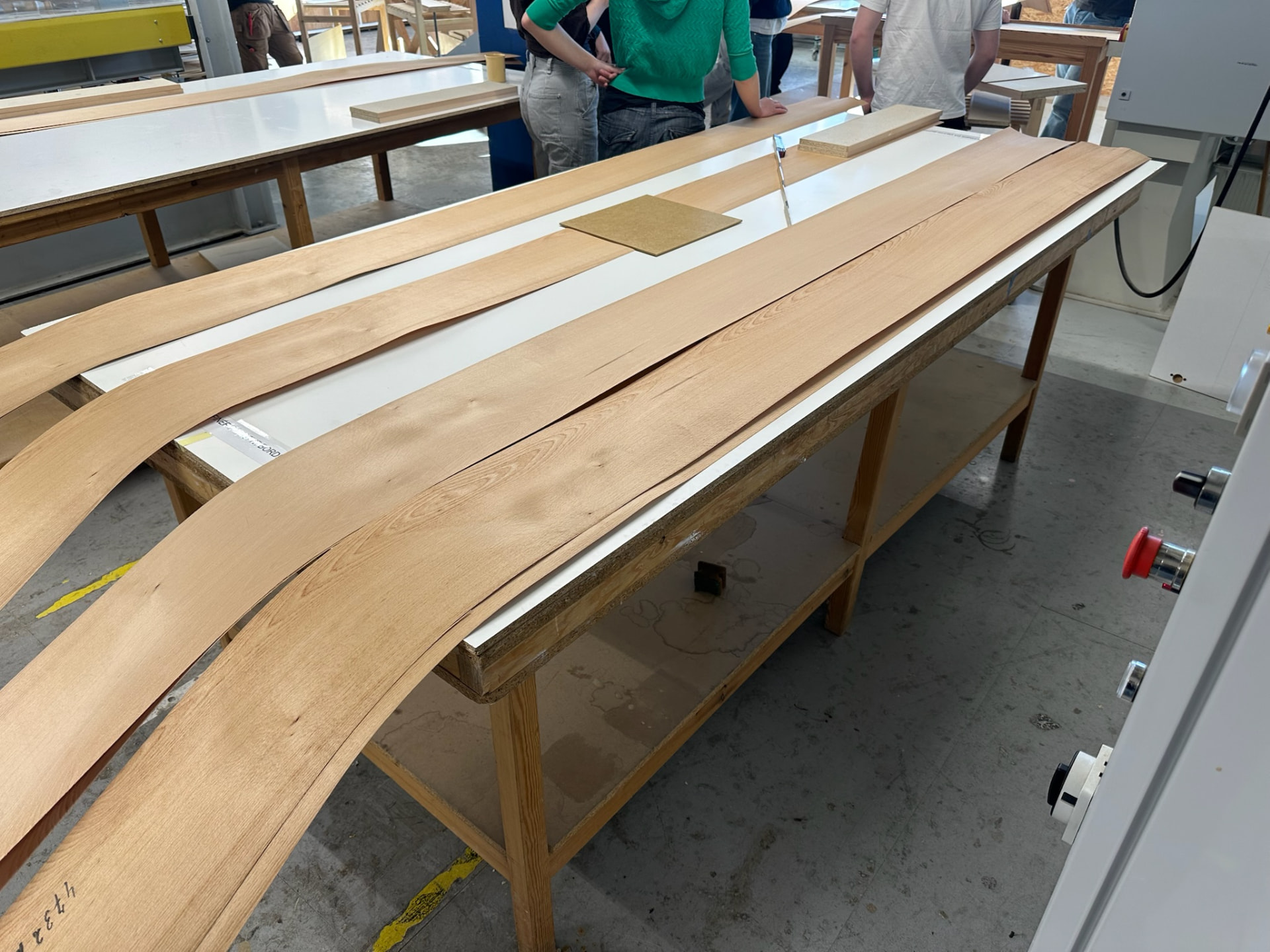 Long sheets of veneer laid out across the workshop benches.